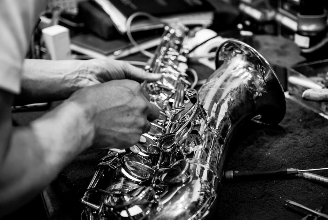 Close-up of hands repairing a saxophone